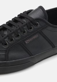 Black leather sneaker with textured upper, round toe, black laces, and silver eyelets; features a small "Superga" logo on the side.