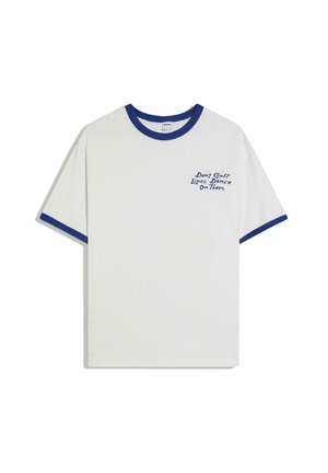 Biała koszulka z niebieskim kołnierzykiem i brzegami rękawów, z niebieskim napisem na lewej piersi: „Don't Cross lines, Dance On Them.”