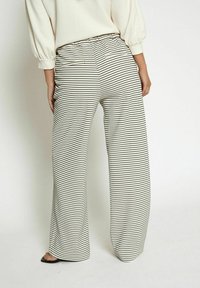 Wide-leg trousers featuring a black and white striped pattern, elastic waistband, and soft, textured fabric. Suitable for casual wear.