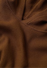 Bruin getextureerde stof met ribbelpatroon, met subtiele V-vormige halslijn en zacht, buigzaam materiaal.