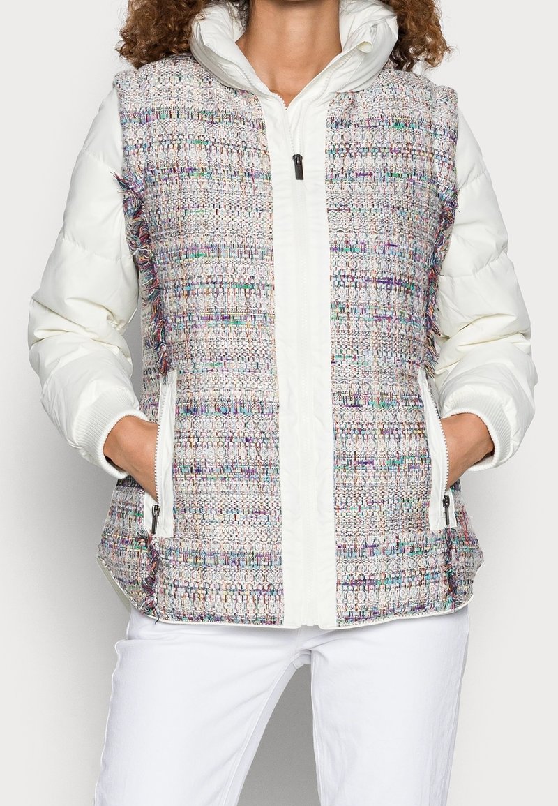 Chaleco de plumas con un frente de tela de tweed multicolor y lados acolchados blancos, que presenta un cierre de cremallera y bolsillos laterales.