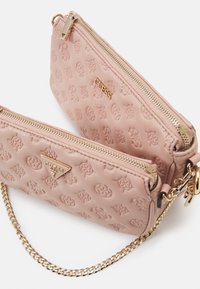 Różowa skórzana saszetka z tłoczonym wzorem logo, złoconymi akcentami, dwoma zamykanymi na zamek przegródkami oraz odczepianym łańcuszkiem.