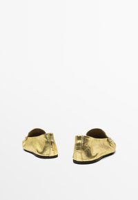 Goldfarbene, metallische Ballerinas mit runder Zehenpartie und glatter, glänzender Oberfläche. Verfügt über einen niedrigen Absatz und ein weiches Innenfutter für zusätzlichen Komfort.