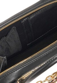 Black leather purse interior with a gold zipper, featuring card slots and a soft black lining. Chain accent attached.
