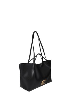 Bolso tote de cuero negro con asas largas y cortas y una letra decorativa dorada C en el lado frontal.