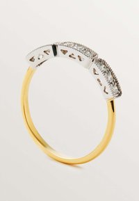 Anillo en tono dorado con una banda de plata texturizada que presenta formas de corazones recortadas y pequeñas piedras claras a lo largo del borde superior.