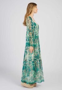 Robe longue et légère en tissu transparent turquoise avec des motifs floraux, dotée de manches longues et d'un corsage ajusté avec fermeture à lien.