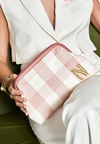 Borsa a quadri rosa e bianca con tessuto texturizzato, bordi rosa e una lettera "N" ricamata in oro su un lato.