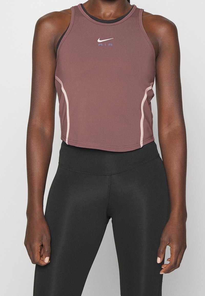 Débardeur crop top Nike de couleur mauve douce, avec un col rond, des coutures contrastantes claires et un logo sur la poitrine.