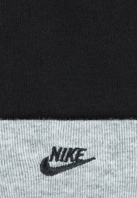 Sorte og grå strikkesokker med en svart Nike-logo brodert på den grå kanten. Teksturen er jevn med et klassisk design.