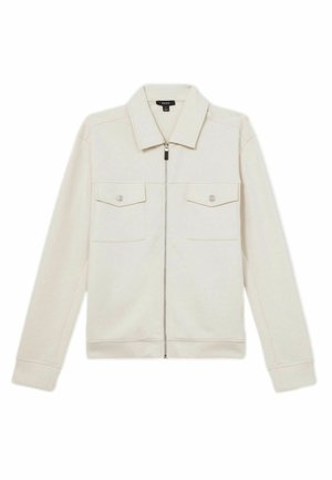 Veste zippée beige clair avec col, deux poches sur la poitrine et poignets côtelés. Fabriquée en tissu doux avec une texture lisse et des coutures subtiles.