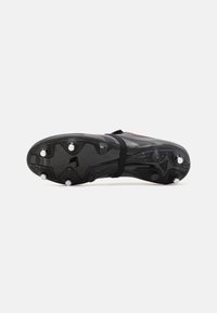 Black football cleat with a textured upper, multiple metal studs, a prominent central band, and subtle red accents on the design.