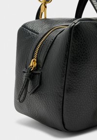 Sac à main en cuir noir avec une finition texturée, dotée d'une fermeture éclair dorée et d'une petite languette en cuir. Forme carrée avec des bords arrondis.