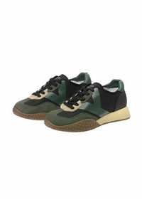 Un paio di sneakers basse con blocchi di colore verde, nero e beige, suole marroni con motivo a nido d'ape e lacci neri su uno sfondo bianco.