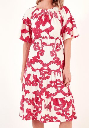Robe en coton avec un motif floral rouge sur fond blanc, manches courtes froncées et jupe à volants.