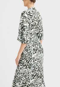Robe fluide en noir et blanc avec un motif abstrait texturé ; dotée de manches courtes volantées et d'une taille cintrée.