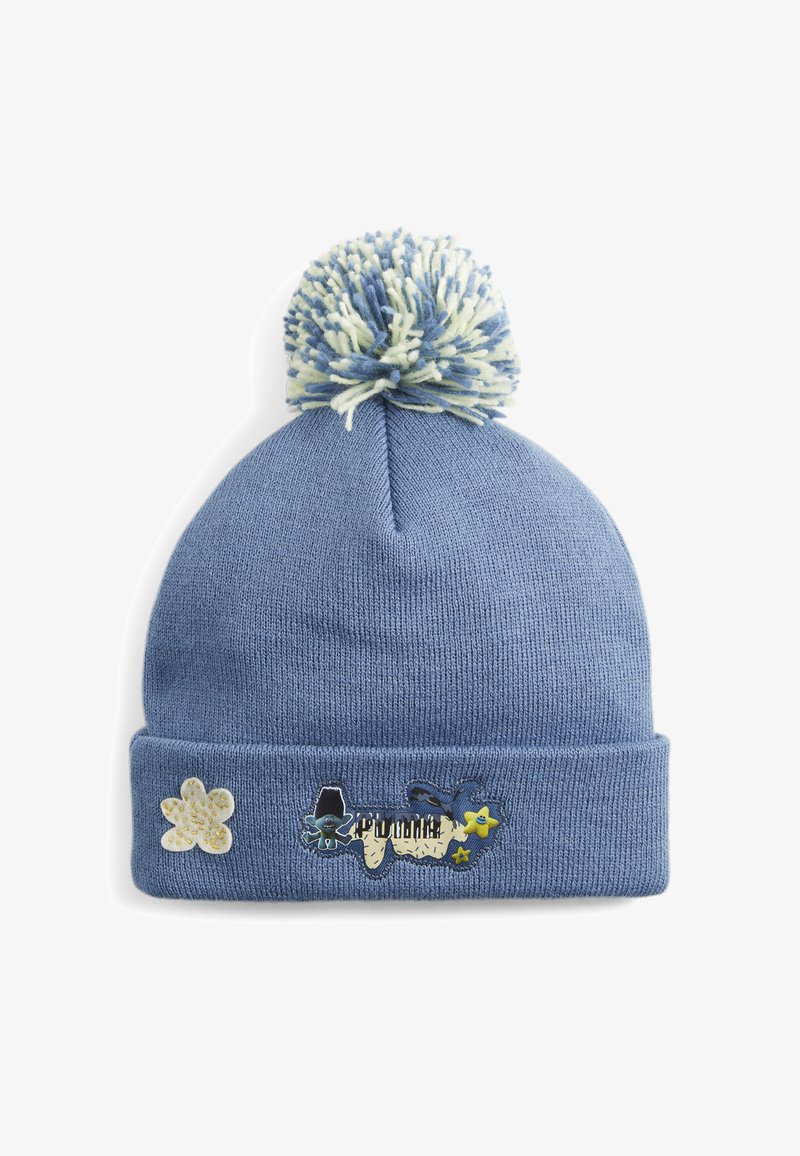 Blue knitted beanie with a pom-pom top, featuring a fold-over cuff and decorative patches: a flower, a cartoon figure, and colorful stars.