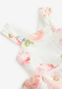 Kukkallinen hihaton mekko läpinäkyvästä, kevyestä kankaasta. Sisältää pastelliväripaletin vaaleanpunaisilla ja sinisillä kukilla sekä ruutukuvion.