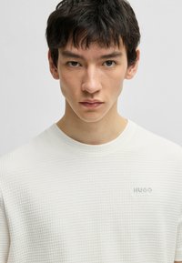 Witte gestructureerde sweatshirt met een ronde hals en subtiele "HUGO" logo in het blauw op de borst. gladde, moderne pasvorm met een ruitpatroon.