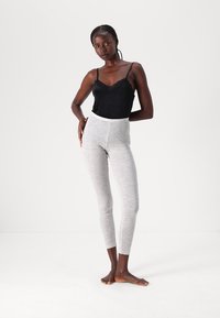 Black lace-trimmed camisole paired with light grey, fitted leggings featuring a heathered texture and high waist design.