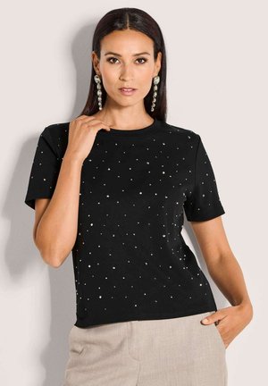 Schwarzes T-Shirt mit kurzen Ärmeln, das mit verstreuten silbernen Verzierungen, einem runden Halsausschnitt und einem lockeren Schnitt ausgestattet ist. Weicher Stoff mit subtiler Textur.