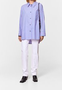 Blue and pink striped long-sleeve shirt with a collar, button front, and a pocket. Paired with white jeans and black heeled boots.