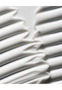 Surface blanche texturée avec des crêtes et des vagues ondulantes, présentant une finition brillante et des contours lisses, sans motifs ou accents distincts.