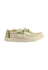 Baskets en toile de couleur beige clair avec des accents verts et un dos à motifs. Caractéristiques : bout arrondi, design à lacets et semelle texturée.