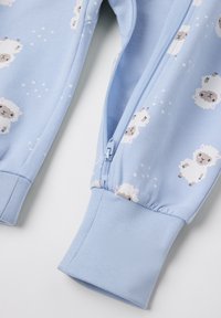 Lichtblauwe pyjamabroek met een rits en geribbelde boorden, voorzien van een patroon van cartoon-schapen op de stof. Zachte, gladde textuur.