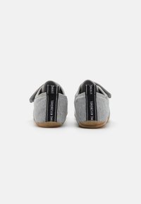 Grå tekstil slip-on sko med en myk overdel, med en teksturert overflate og en svart-hvit etikett på hælen. Gummisåle.