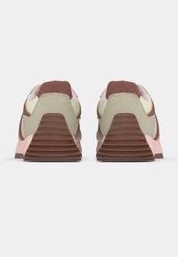 Αθλητικό παπούτσι σε κρέμ, καφέ και ροζ χρώμα με πολυστρωματική σόλα, υφασμάτινες λεπτομέρειες και στρογγυλεμένο σχέδιο μύτης με ορατά κορδόνια και υλικά από ύφασμα.