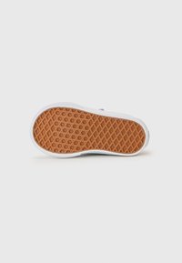 Semelle en caoutchouc avec un motif en chevrons marron, entourée d'une bordure blanche. Le dessous présente un design de grip texturé pour une meilleure adhérence.
