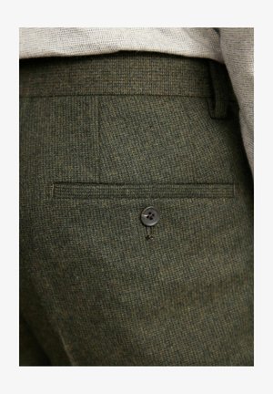 Zelené textúrované nohavice s jednou zadnou vreckom a tmavým gombíkom, vyrobené z jemne vzorovanej látky. Priliehavý strih pre pohodlie.