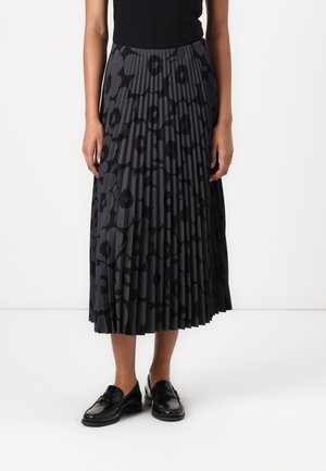 Pleated skirt with a dark floral pattern in shades of gray, made from a lightweight fabric. Paired with black, polished loafer shoes.