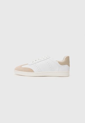 Sneakers bianchi con accenti in suede beige, parte superiore in pelle liscia, design perforato sui lati, suola bianca piatta e chiusura con lacci.
