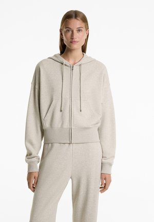 Light gray zip-up hoodie made of soft fabric, featuring a front pocket, drawstring hood, and ribbed hem and cuffs.