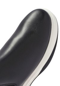 Black leather shoe with smooth texture, rounded toe, and white sole. Minimalist design with no visible patterns or hardware details.