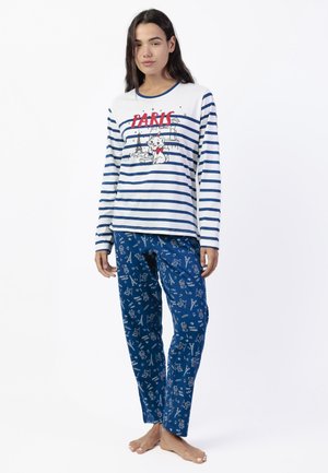 Mujer con camiseta de manga larga a rayas azules y blancas con la palabra "PARIS" y un gráfico de gato, combinada con pantalones azules con ilustraciones temáticas de París.