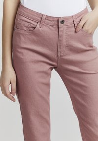 Pantalones de mezcla de algodón rosa claro con un diseño de pierna recta, un bolsillo frontal único y un cierre de botón, que presentan una sutil textura y detalles de costura.