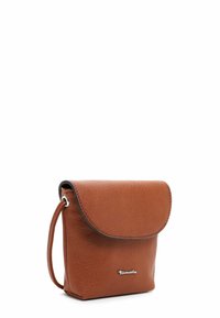 Hnědá kožená crossbody taška s překlopným víkem, stříbrným logem a texturovaným povrchem. Malý, obdélníkový tvar s ramenním popruhem.