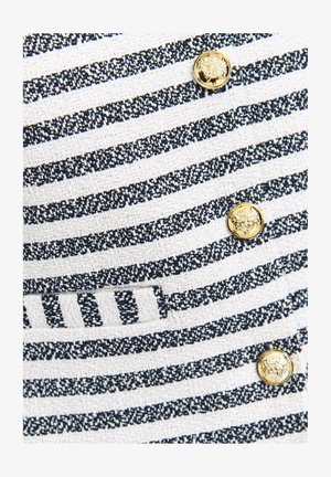 Textured fabric featuring alternating navy and white stripes, with gold buttons displaying a lion motif, adding contrast and detail.