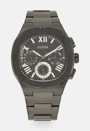 Montre en acier inoxydable noir avec un cadran gris texturé, des chiffres romains, trois sous-cadrans et un bracelet solide. Accents de design hexagonal distinctifs.