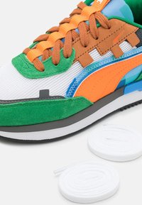 Baskets multicolores en mesh et daim, avec des accents orange, vert et bleu. Comprend des lacets blancs et une semelle texturée.