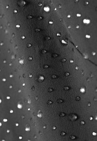 Material impermeabilizat de culoare neagră, cu picături mici de apă, evidențiind o suprafață texturată cu o combinație de zone netede și ridicate.