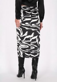 Fustă midi cu un model alb-negru, având un design ondulat, fabricată dintr-un material neted, cu o deschidere la spate și o siluetă ajustată.