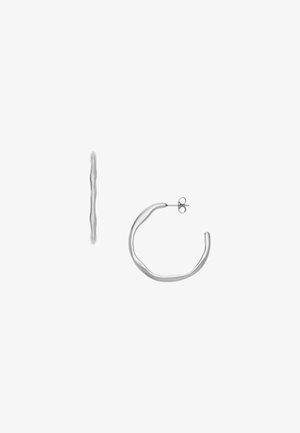 Boucles d'oreilles en argent avec un design ondulé, une forme fine et un fermoir à tige sécurisé. Texture lisse avec une surface réfléchissante.