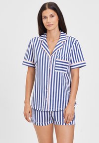 Cotton pajamas set featuring blue and white vertical stripes, short sleeves, and a chest pocket. Pink trim along the collar and sleeves.