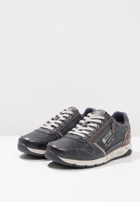 Baskets en cuir gris avec des lacets blancs, des accents rouges et argentés, une fermeture éclair sur le côté et une semelle rembourrée. Présentent un logo sur le côté.