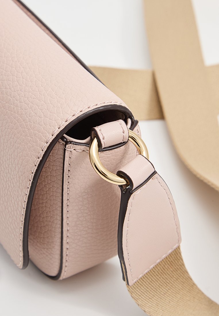 Sac à main en cuir texturé rose avec un détail de quincaillerie en anneau doré et une bandoulière contrastante en cuir tan. Forme arrondie avec des bords finement finis.