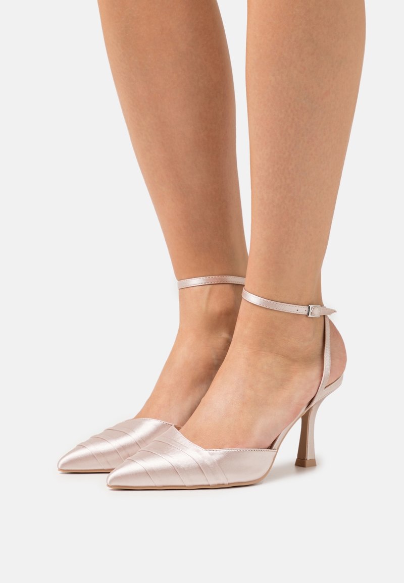 Chaussures à talons hauts en satin rose avec bouts pointus, munies d'une fine bride autour de la cheville et de fines rayures verticales sur la tige.